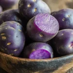 Freshly harvested purple potatoes in a rustic bowl.