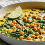Creamy chickpea spinach skillet in a white pan with fresh herbs on top.