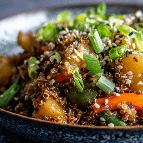 Bowl of colorful veggie quinoa stir fry in a bright modern kitchen.