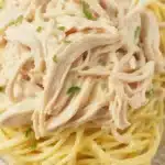 Creamy crockpot angel chicken served over angel hair pasta with vegetables.