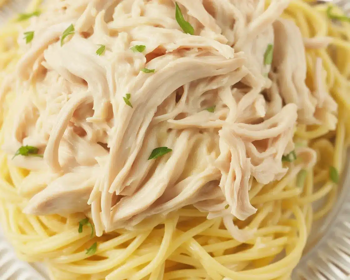Creamy crockpot angel chicken served over angel hair pasta with vegetables.