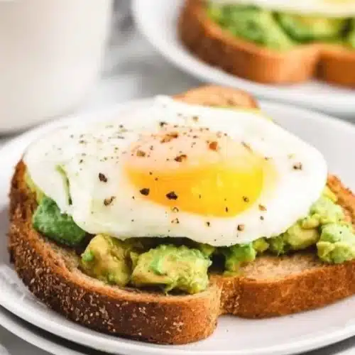 Delicious avocado toast topped with a perfectly fried egg on a rustic plate