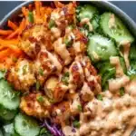 Delicious Bang Bang Chicken Bowl topped with spicy sauce and fresh vegetables.