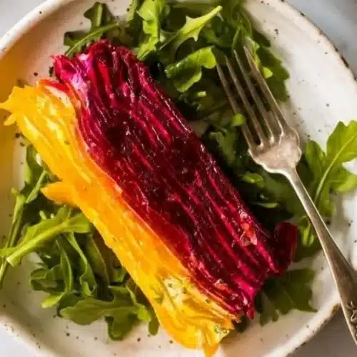 Sliced beet terrine layered with herbed goat cheese, showcasing vibrant colors.