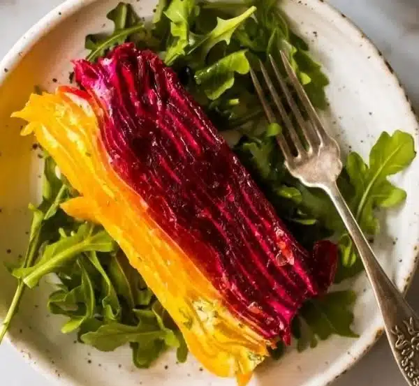 Sliced beet terrine layered with herbed goat cheese, showcasing vibrant colors.
