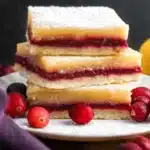 Delicious homemade Cranberry Lemon Bars on a white plate with fresh cranberries