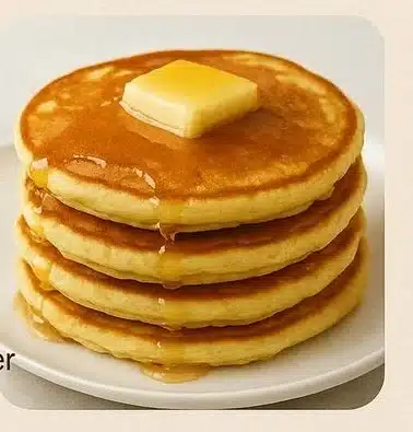 Stack of easy fluffy pancakes with syrup and berries on a plate