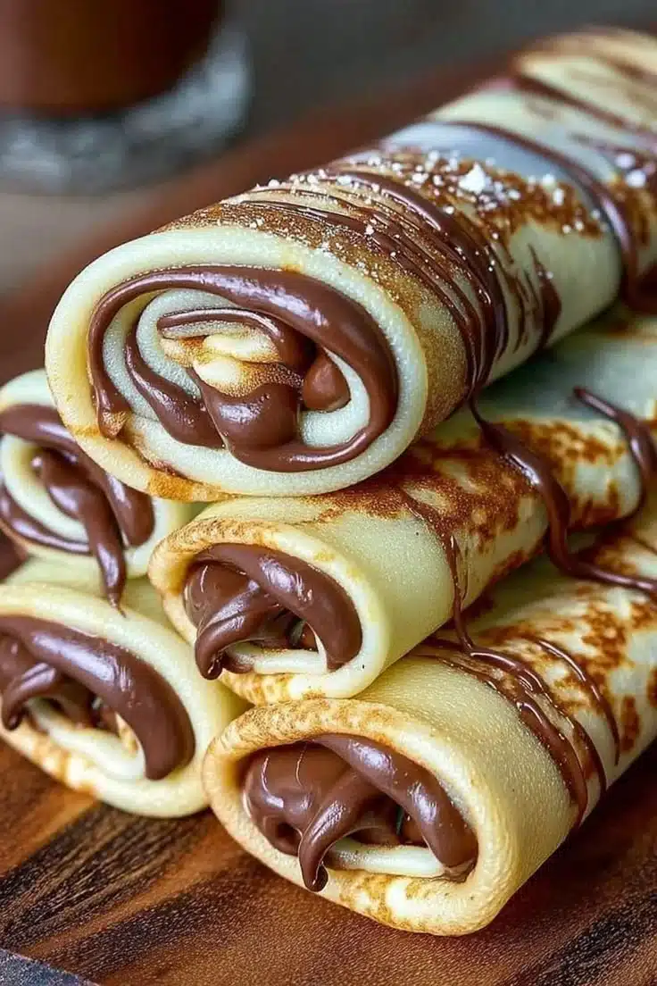 Handmade chocolate-filled rolled crêpes served with a drizzle of chocolate sauce