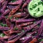 Plate of purple sweet potato fries with herby tahini sauce dipping