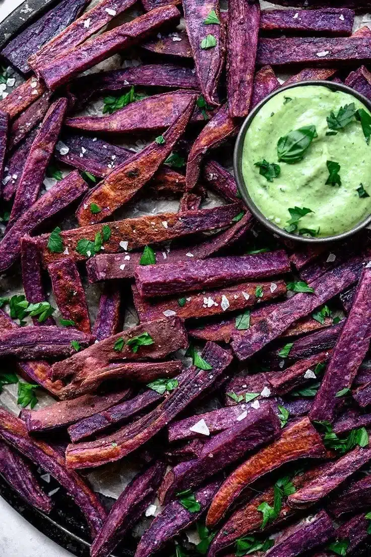 Plate of purple sweet potato fries with herby tahini sauce dipping