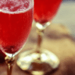 Raspberry Champagne cocktail garnished with fresh raspberries and mint leaves