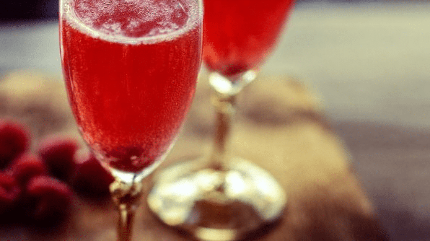 Raspberry Champagne cocktail garnished with fresh raspberries and mint leaves