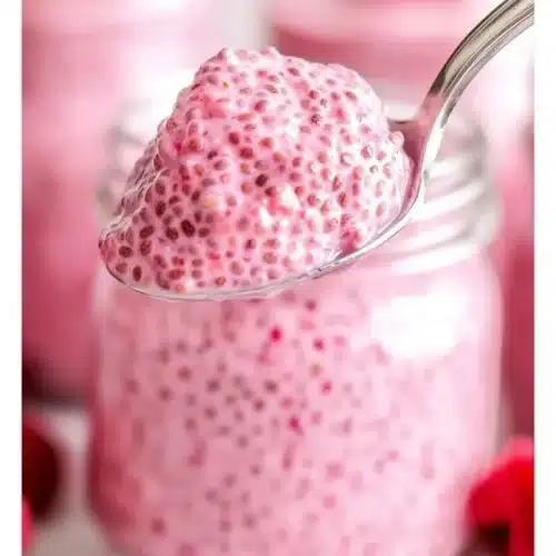 Raspberry chia pudding topped with fresh raspberries and drizzled with maple syrup