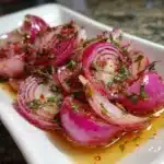 Hot Honey Pickled Red Onions in a jar with spices and honey drizzle.