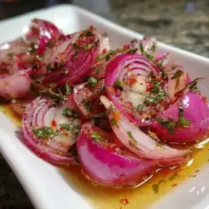 Hot Honey Pickled Red Onions in a jar with spices and honey drizzle.