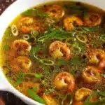 Miso-Ginger Lemon Shrimp Detox Broth in a bowl garnished with herbs.