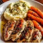 Plate of Garlic Herb Chicken with creamy mashed potatoes and glazed carrots