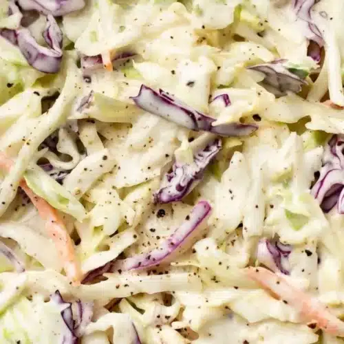 Bowl of colorful coleslaw with cabbage, carrots, and dressing