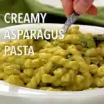 A delicious plate of creamy asparagus pasta garnished with herbs.