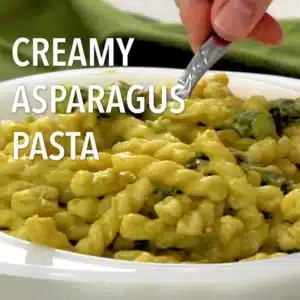 A delicious plate of creamy asparagus pasta garnished with herbs.