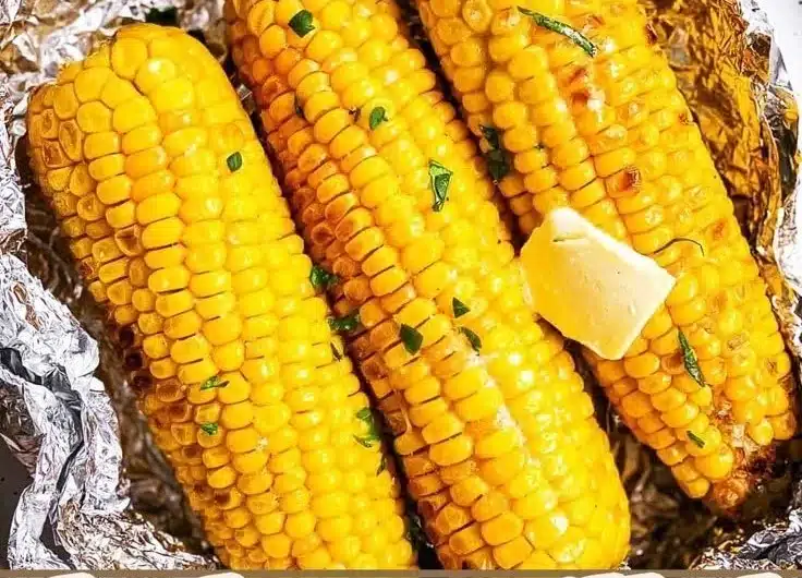 Grilled corn on the cob wrapped in foil for BBQ cooking