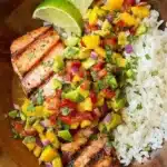 Grilled salmon topped with mango salsa served alongside coconut rice