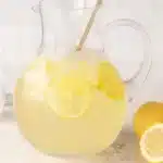 A refreshing glass of homemade lemonade with lemons and mint leaves