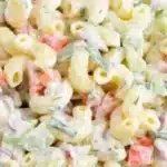 Delicious homemade macaroni salad served in a bowl with fresh vegetables.