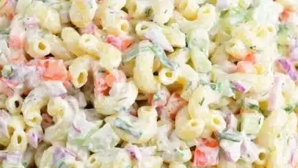 Delicious homemade macaroni salad served in a bowl with fresh vegetables.